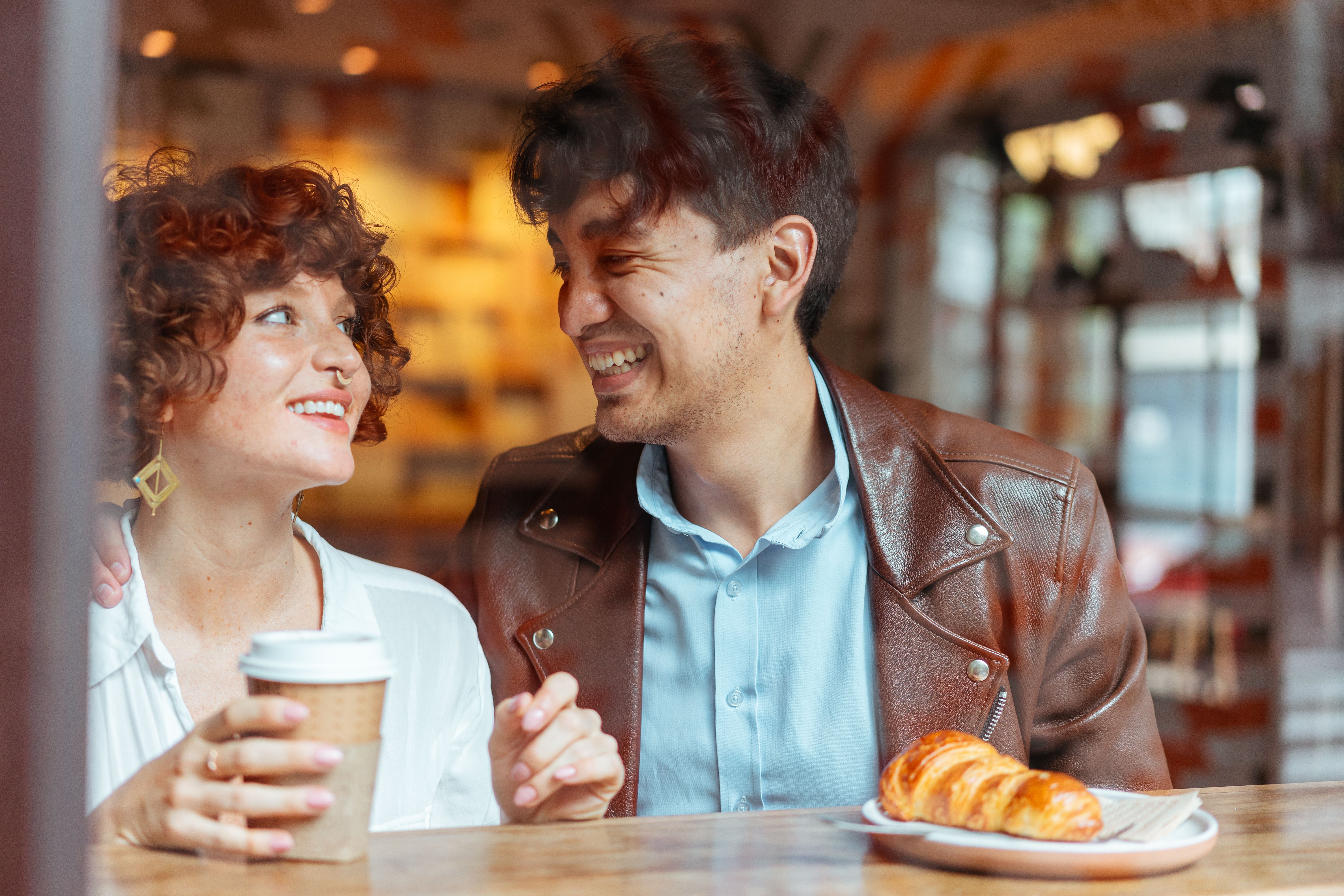 Couple laughing and enjoying coffee together at a cozy cafe on a modern first date