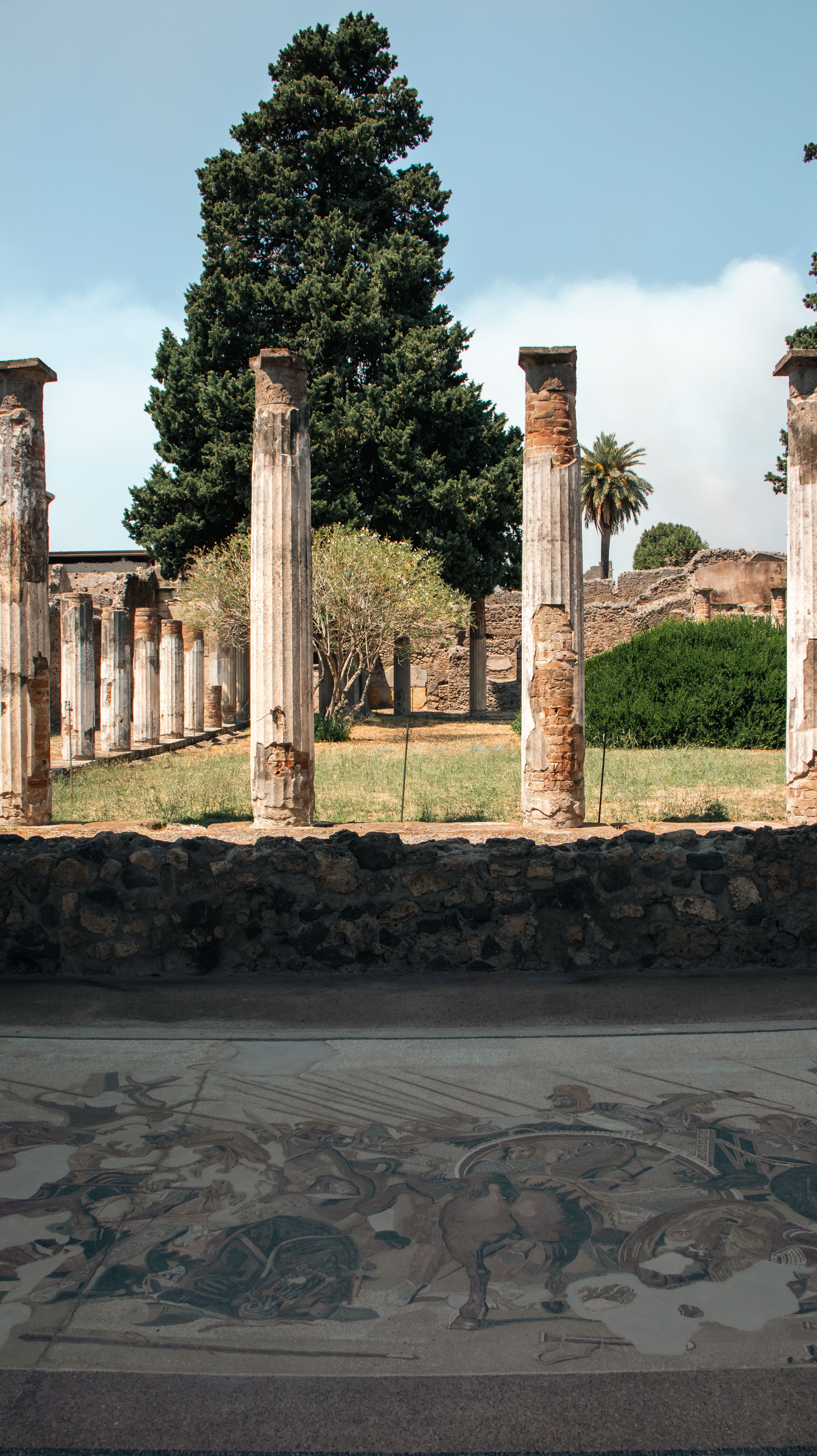 Ancient ruins with columns and mosaic floor in Pompeii, Italy, showcasing Roman architecture