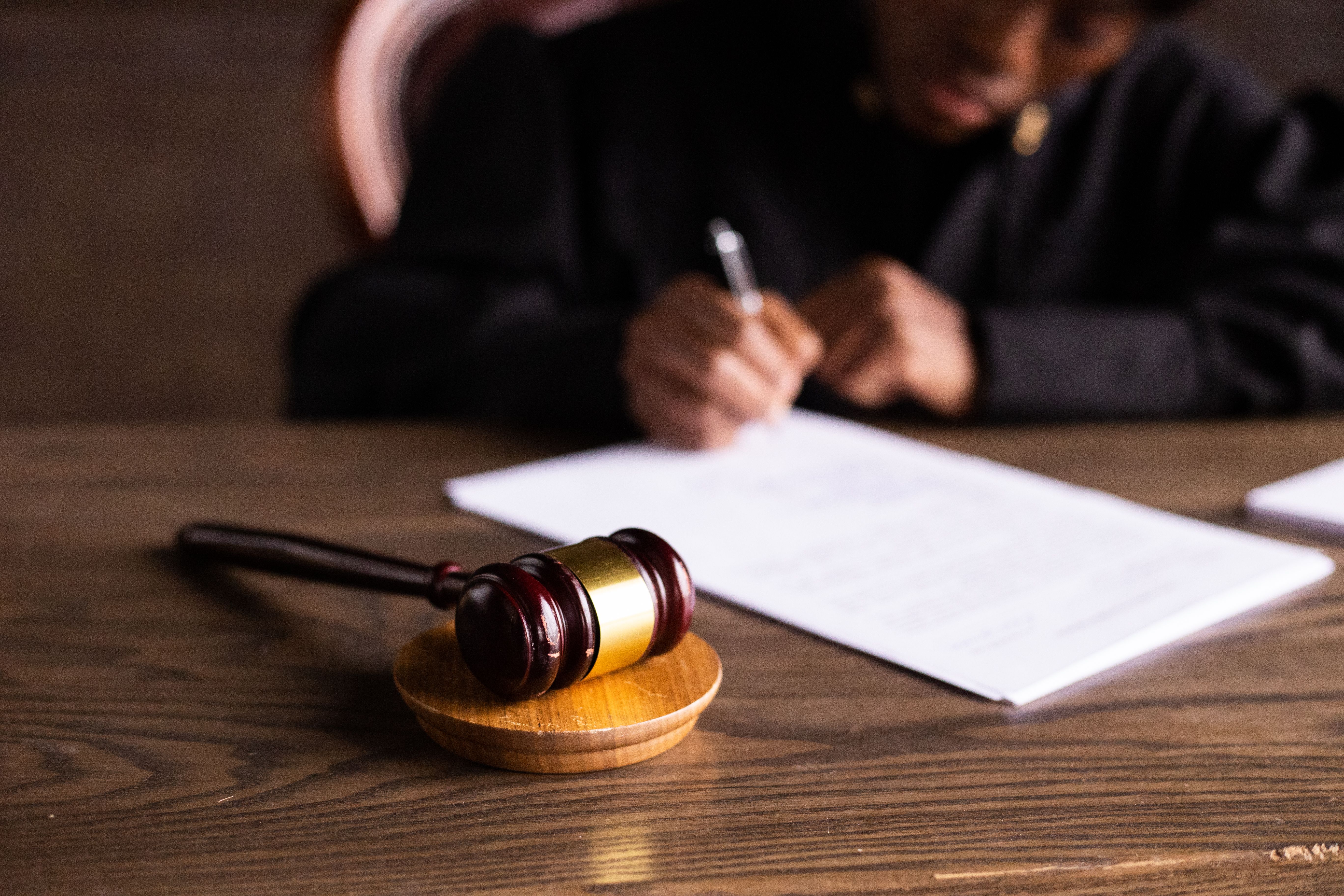 Judge signing legal documents beside a gavel, representing a civil lawsuit judgment.