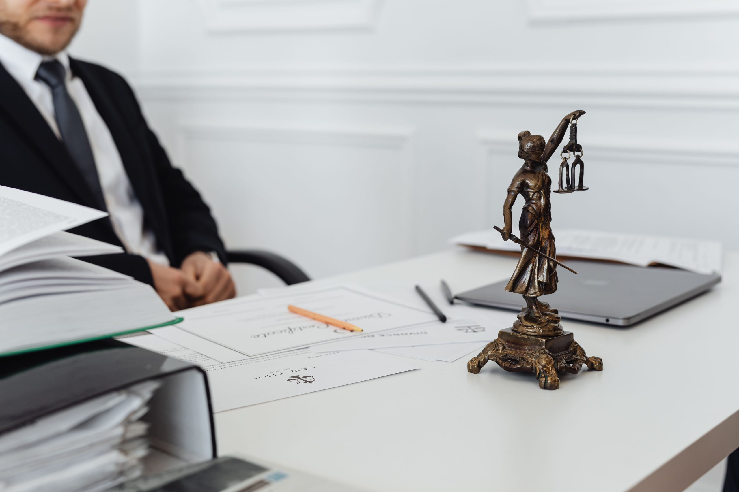 Legal professional's workspace with Lady Justice, court documents, and a laptop representing the start of a civil lawsuit.
