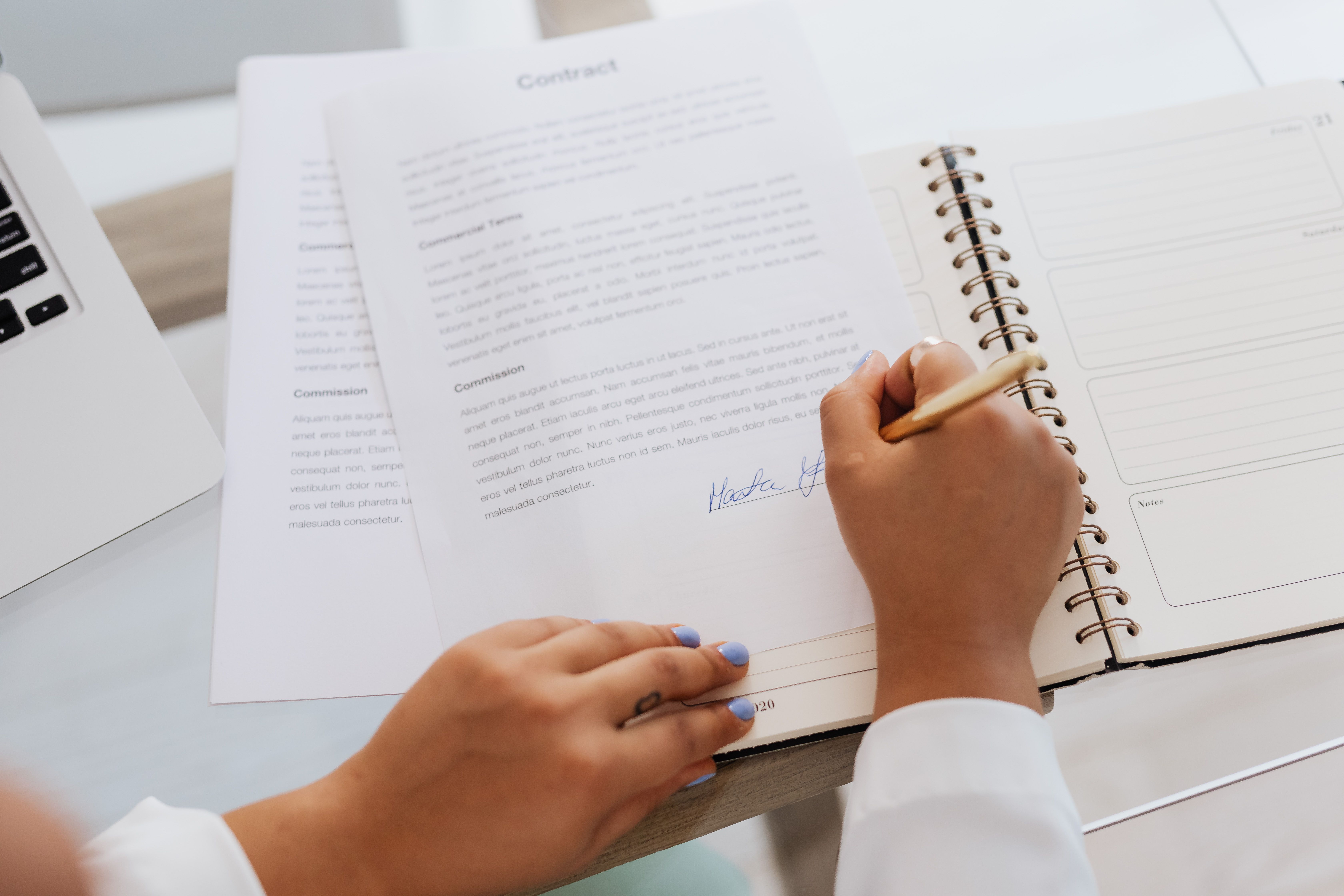Hands signing a contract on a desk, symbolizing a settlement agreement in a civil lawsuit.